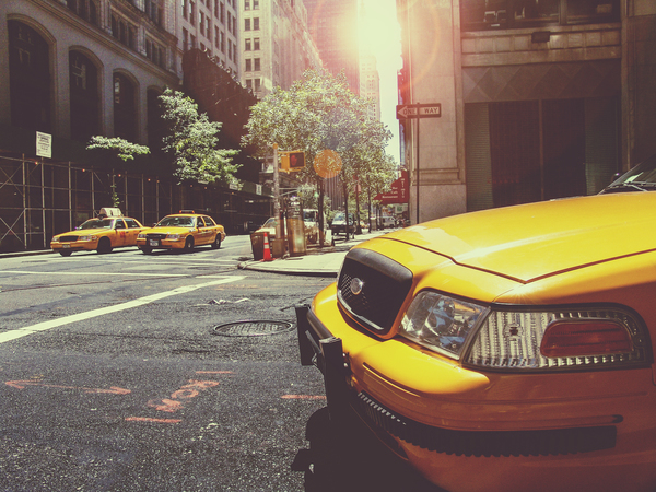 yellow,taxis,cabs,new york,city,streets,roads,intersection,buildings,towers,signs,cars,pavement,manhole