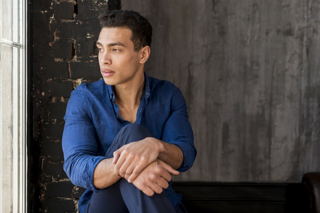 Free Stock Photo of Young Man sitting near window