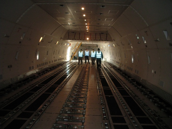 plane,aeroplane,airplane,aviation,cargo,hold,interior,tunnel,men,workmen,vest,hivis,high,visibility,aircraft,bolts,four,light,glow