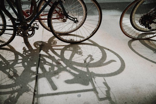  rim,bike,wire,pole,park,wheel,shadow,pedals, pavement