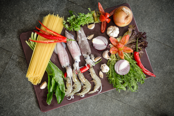 food,platter,fish,squid,ingredients,vegtables,wood,table,spaghetti,onion,salad,lettuce,garlic