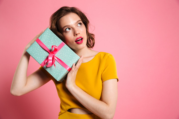 Free: Young charming woman in yellow dress holding gift box