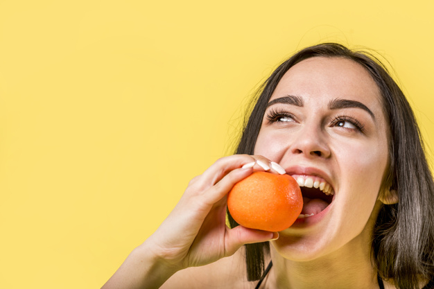 unpeeled,studio shot,manicured,copy space,biting,ripe,enjoying,refreshing,juicy,brunette,cheerful,tangerine,mandarin,citrus,copy,pretty,horizontal,shot,holding,delicious,vitamin,lifestyle,beautiful,fresh,young,eating,female,studio,open,healthy,mouth,sweet,teeth,natural,yellow background,person,yellow,happy,orange,space,fruit,woman,summer,hand,food,background