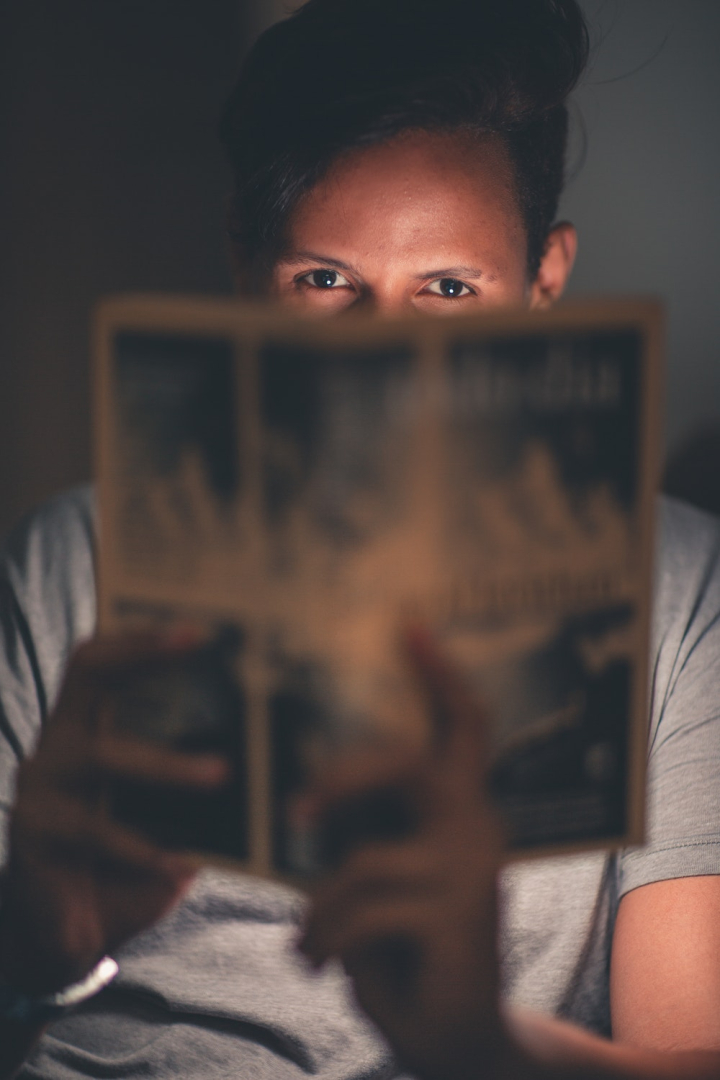 adult,blur,book,facial expression,focus,indoors,light,man,person,portrait,reading,room,wear