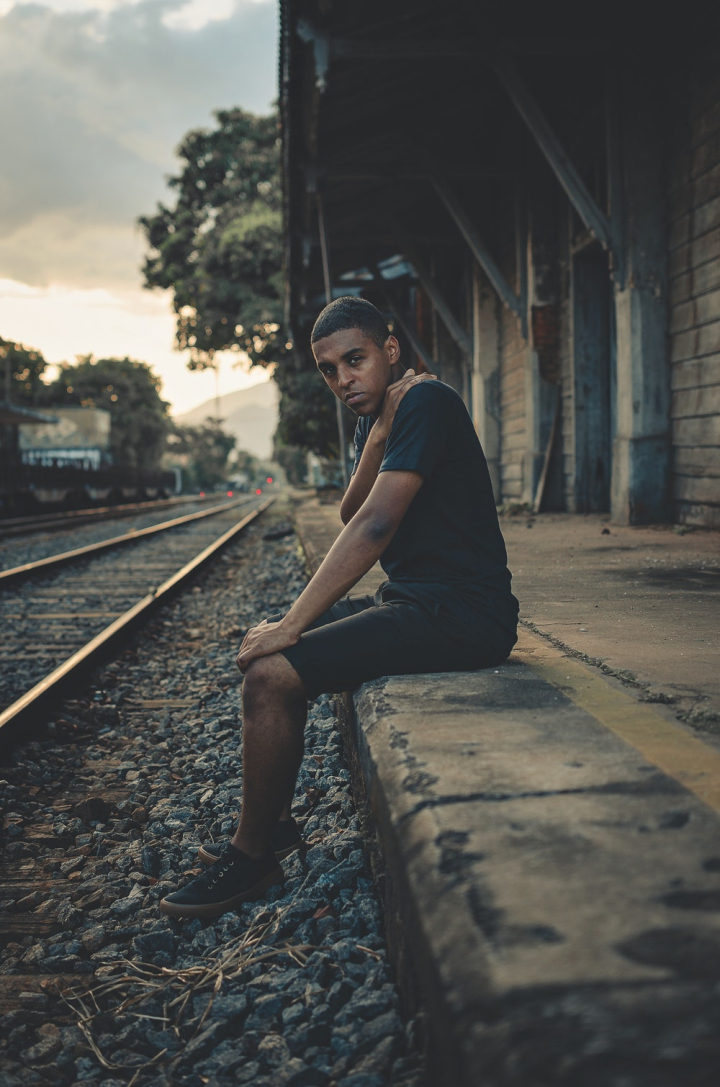 Photo of a man sitting on train tracks with a defiant pose Stock Photo -  Alamy