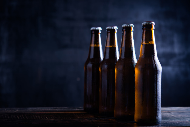 Cold beer with foam in a mug, on a wooden table and a dark background with