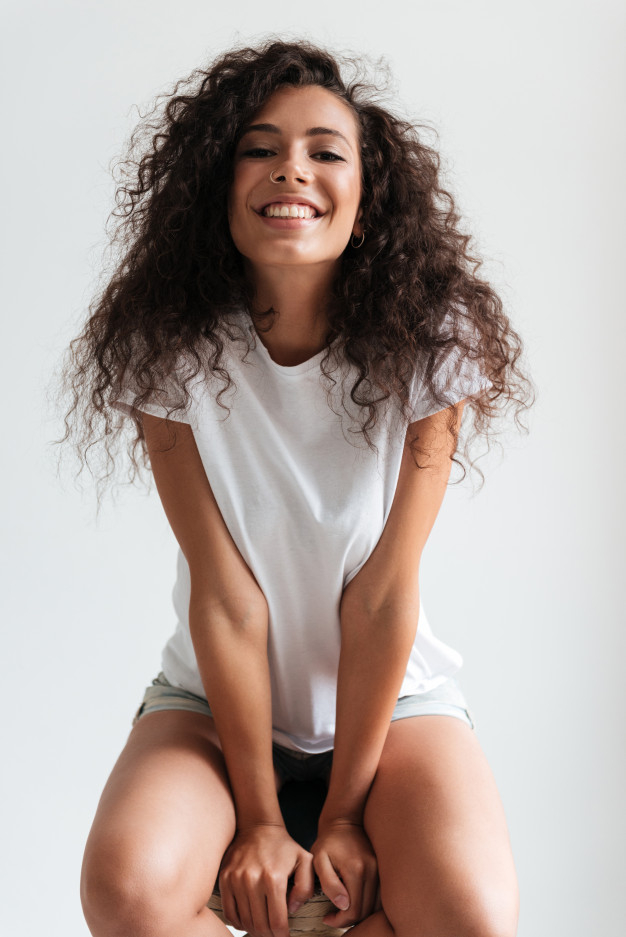 haircare,styling,posing,joyful,brunette,attractive,cheerful,perfect,smiling,pretty,laughing,adult,curly,portrait,sitting,beautiful,wellness,hairstyle,young,female,youth,healthy,chair,natural,person,happy,face,hair,woman,hand