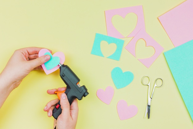 Woman glues pasta with a hot glue gun during the manufacture of crafts  Stock Photo