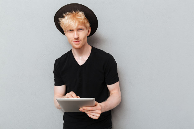 caucasian,attractive,blonde,casual,handsome,chatting,standing,looking,adult,guy,pocket,male,arm,sms,portrait,cool,young,relax,youth,hat,tablet,person,human,student,man,computer,people