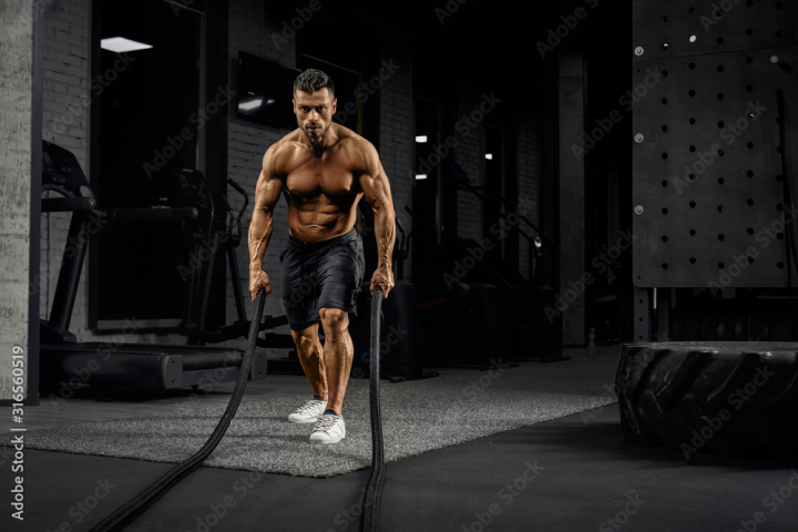 exercise,gym,physical exercise,strength,sport,muscular,man,powerful,fit,healthy,young,cardio,rope,strong,1,active,fitness,attractive,body,athlete,energy,equipment,adult,motivation,male,contrast,person,activity,concentration,training,power,club,people,caucasian,bodybuilder,force,facial expression,indoor,dark,front view,horizontal,motion,shirtless,half-naked,adobestock