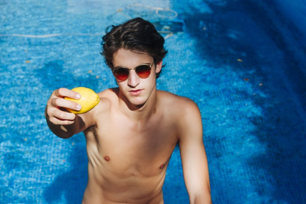 Free: Young man wearing sunglasses showing lemon in swimming pool Free  Photo 