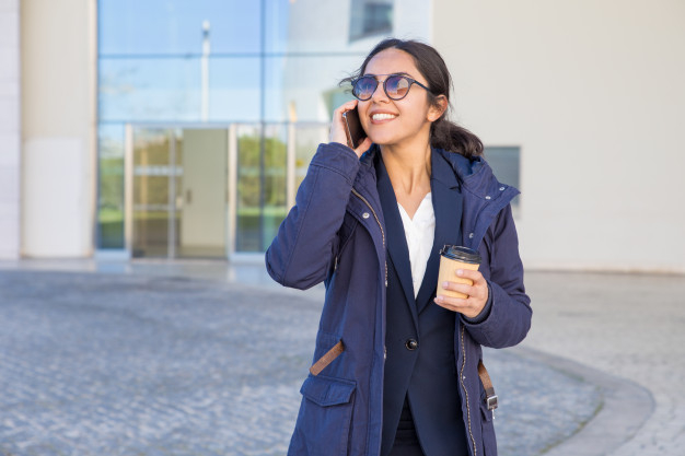 overjoyed,toothy,parka,joyful,cheerful,casual,takeaway,excited,great,standing,smiling,busy,center,formal,adult,businesswoman,sharing,speaking,joy,break,positive,cell,portrait,good,professional,young,cellphone,talking,female,outdoor,morning,walking,suit,lady,sunglasses,call,news,communication,person,happy,mobile,office,girl,phone,woman,city,coffee,business