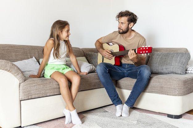 indoors,husband,togetherness,daughter,living,playing,horizontal,male,lifestyle,sitting,dad,carpet,together,sofa,father,guitar,room,home,girl,man,family,house