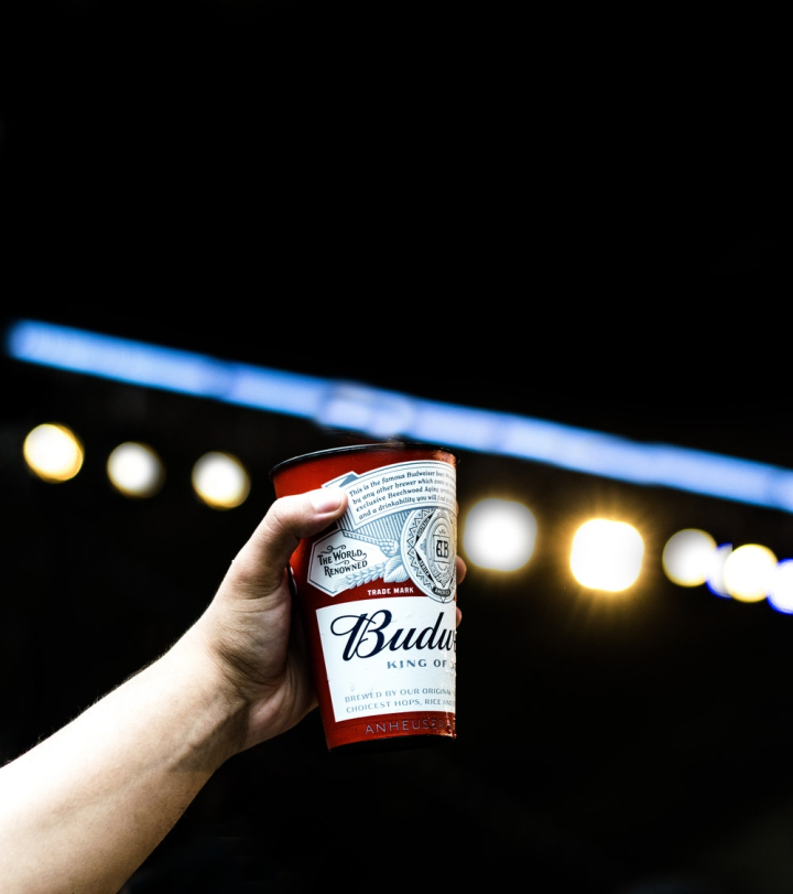 alcoholic beverage,beer,blur,cup,drink,focus,hand,illuminated,lights,liquor,person