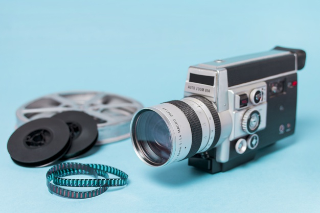Free: Film reels; film strips and vintage camcorder on blue