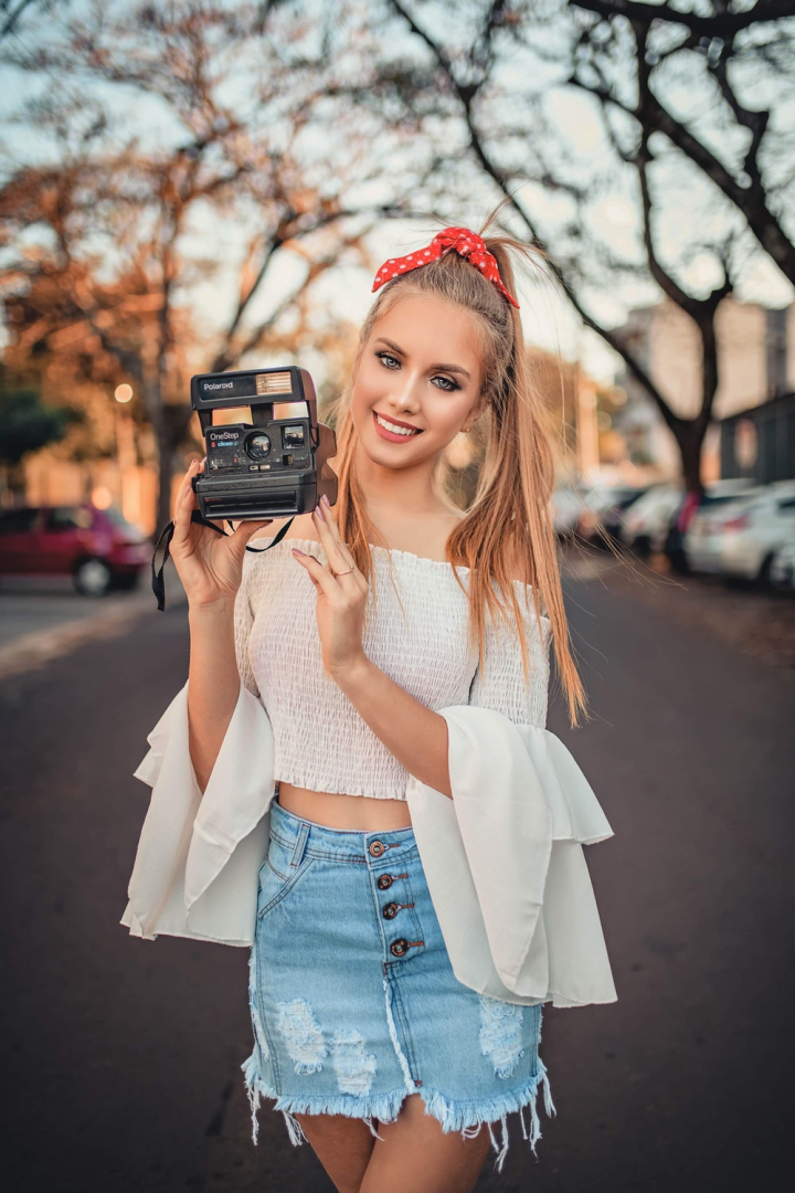 beautiful,beauty,blond hair,blonde,blur,depth of field,facial expression,fashion,female,focus,hairstyle,hands,happy,holding,instant camera,model,modeling,outdoors,outfit,photo session,photo shoot,polaroid,posing,pretty,ribbon,smile,smiling,standing,style,woman