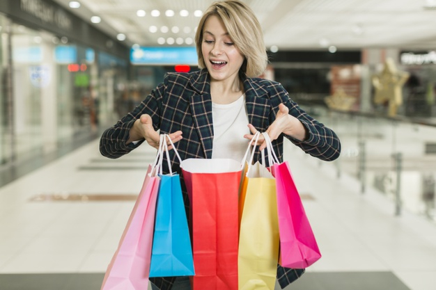 Happy Woman Holding A Lot Of Clothes At Store And Smiling Stock