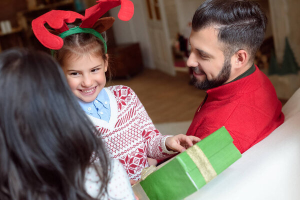 happiness,preteen,New Year,Caucasian girl,winter,festive,xmas,season,child,european,merry,caucasian woman,present,parenthood,family,daughter,greeting,kid,event,father,parents,celebration,happy,celebrate,antlers,indoors,hold,smile,holiday,christmas,traditional,gift box,mother,christmas eve,Young Adults,childhood,at home,Caucasian Man,Cropped,people,christmastime,depositphotos