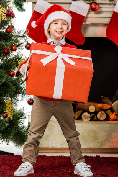 decor,smiling,fireplace,present,New Year,box,alone,gift,festive,adorable,sweater,holiday,preteen,santa hat,greeting,child,christmas tree,merry,person,christmastime,male,happiness,decorated,caucasian boy,christmas eve,merry christmas,people,xmas,smile,happy,kid,depositphotos