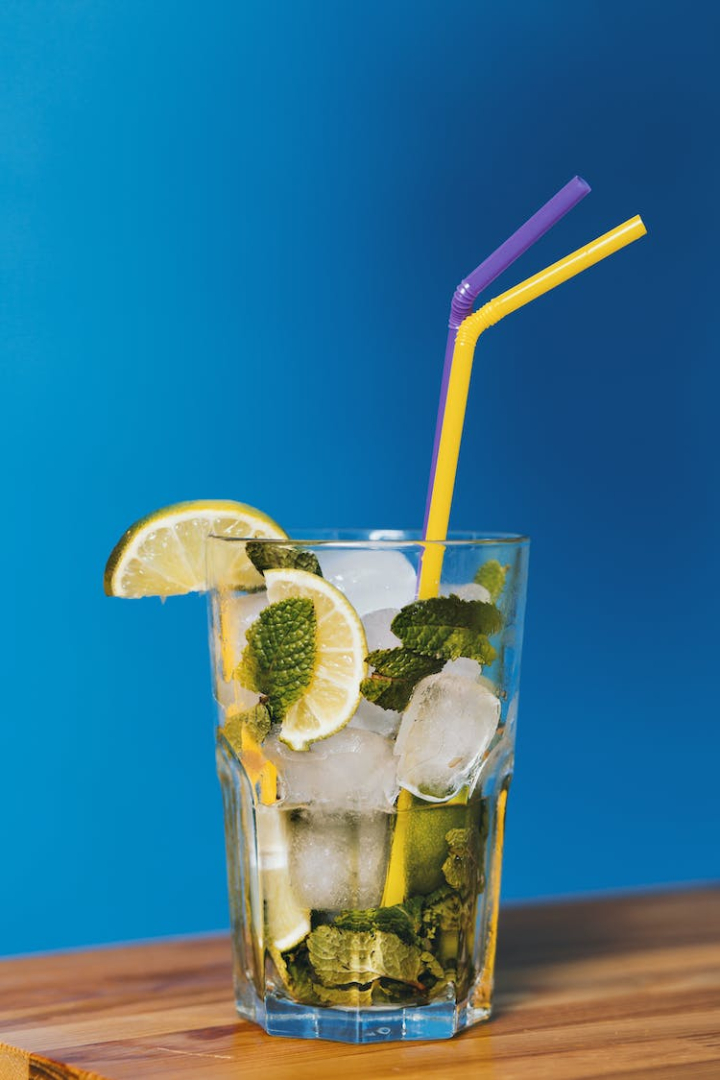 alcoholic beverage,beverage,blue background,close-up,cocktail,cold,cool,drink,drinking straw,fresh,fruit,glass,ice,ice cubes,juice,lemon,lemonade,lime,liquid,liquor,mint,mint leaves,mojito,party,refreshing,refreshment,straws,summer,table,vodka