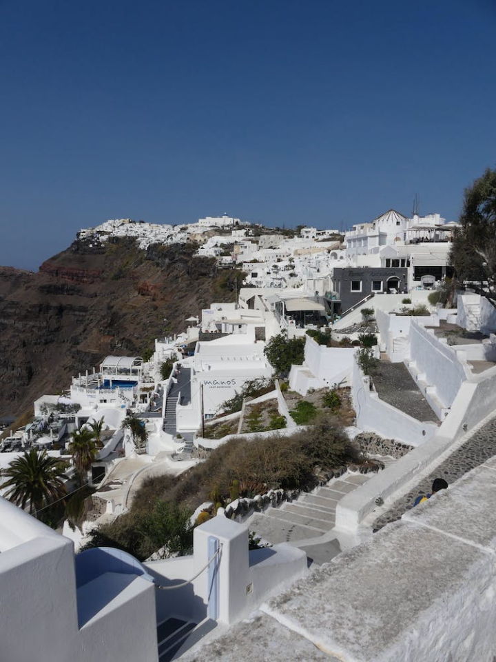 architecture,blue sky,buildings,concrete,greece,high angle shot,houses,mountain,santorini,stairs,steps,town,vertical shot