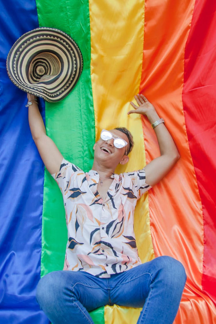 gay pride flag,lgbt flag,man,pride,rainbow flag,smiling,straw hat,sunglasses,vertical shot