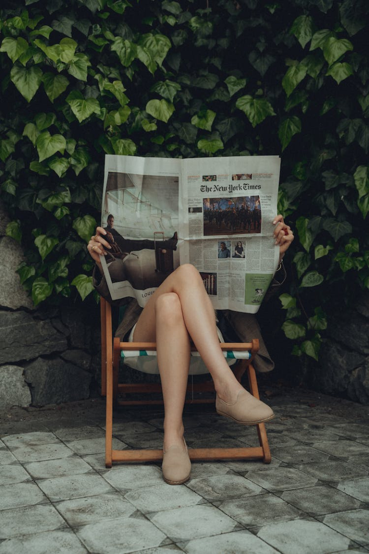 garden,lounge chair,newspaper,reading,relaxation,sitting,summer,vertical shot,woman,young