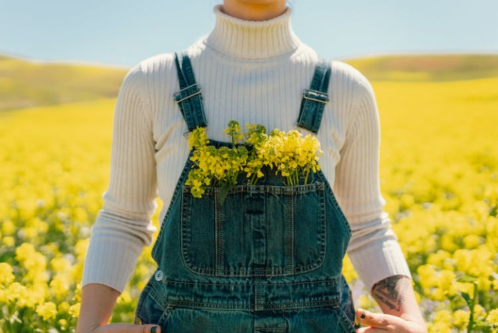 blooming,blossom,close up,denim dungarees,flower field,front view,in bloom,oilseed,person,rapeseed,spring,super bloom,superbloom,unrecognizable,yellow flowers