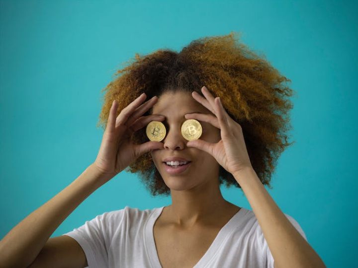 afro,afro hair,attractive,beautiful,beauty,bitcoin,blue background,casual,coins,crypto,cryptocurrency,eyes,face,female,hair,holding,in front of,person,portrait,pretty,t shirt,white t shirt,woman