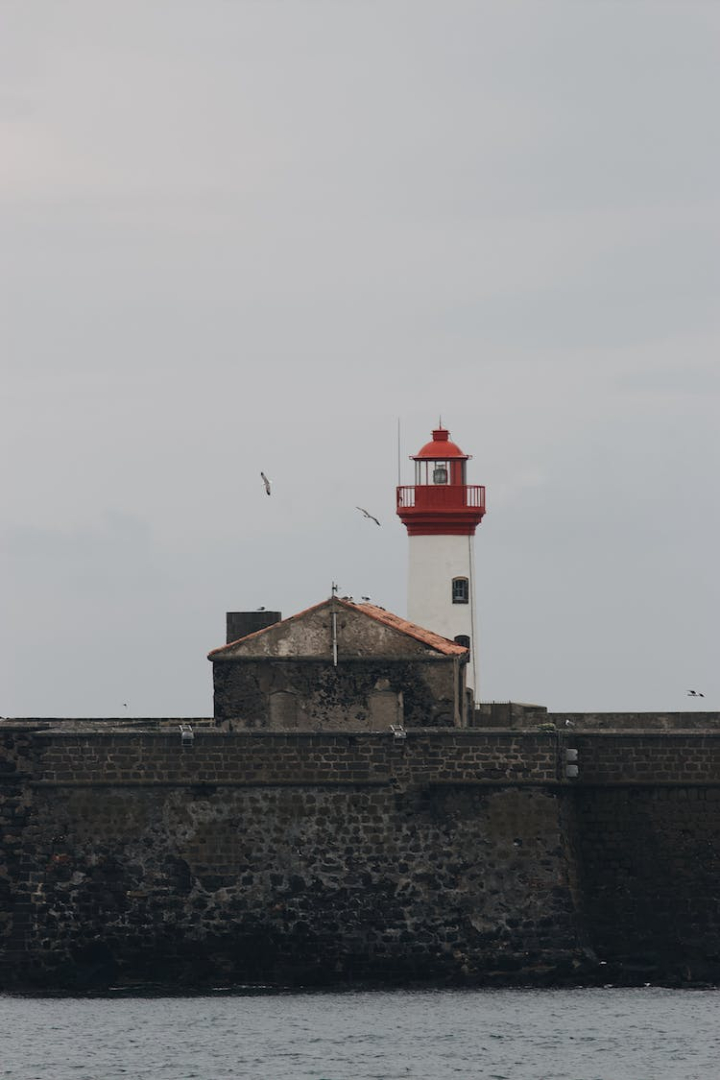 architecture,beacon,bird,building,cloudy,coast,coastline,construction,destination,direction,dull,embankment,gloomy,gray,guide,harbor,infrastructure,lighthouse,location,marine,nautical,navigate,ocean,outdoors,overcast,port,safety,sea,seafront,seashore,seaside,security,shore,signal,sky,skyline,stone,stormy,structure,tourism,tower,travel,vertical shot,waterfront
