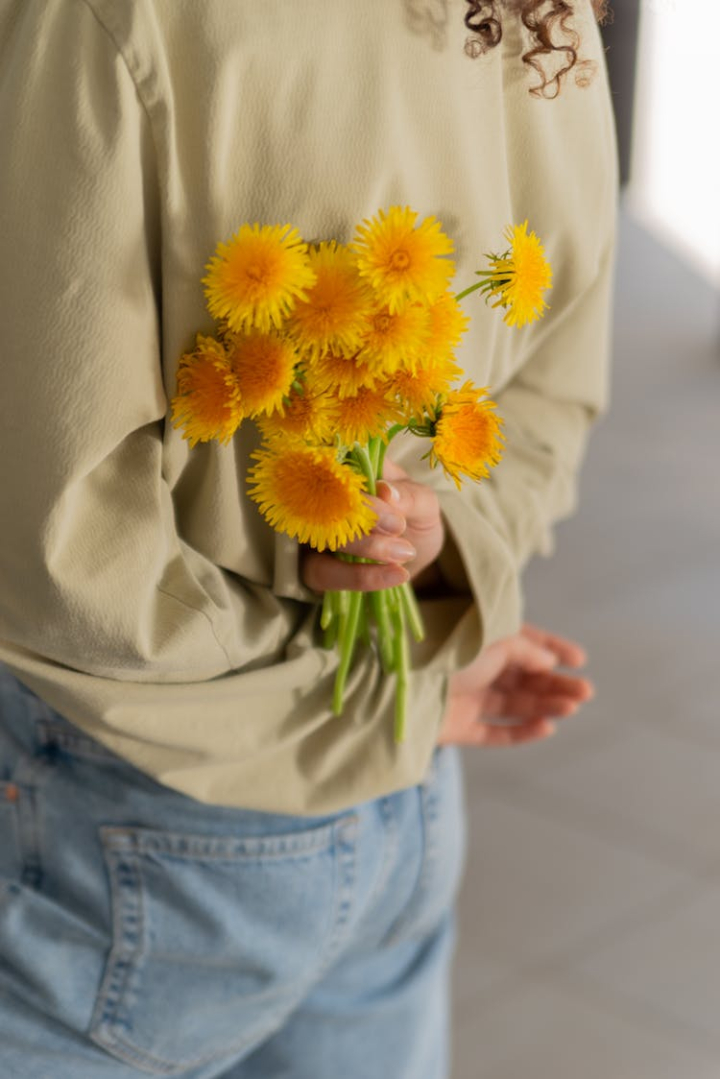 back,bouquet,bunch,fresh,hand,hiding,holding,long sleeves,person,petals,stem,surprise,vertical shot,yellow flowers