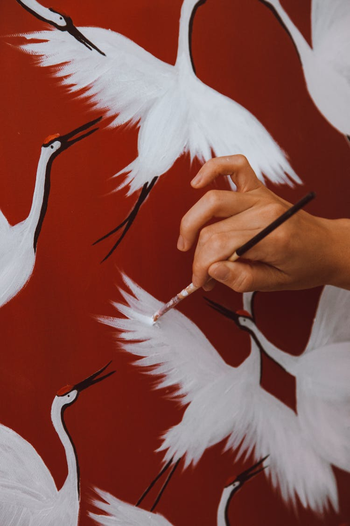 artist,artistic,creative,hand,holding,paintbrush,painting,person,red background,vertical shot,visual art,wall painting,white bird