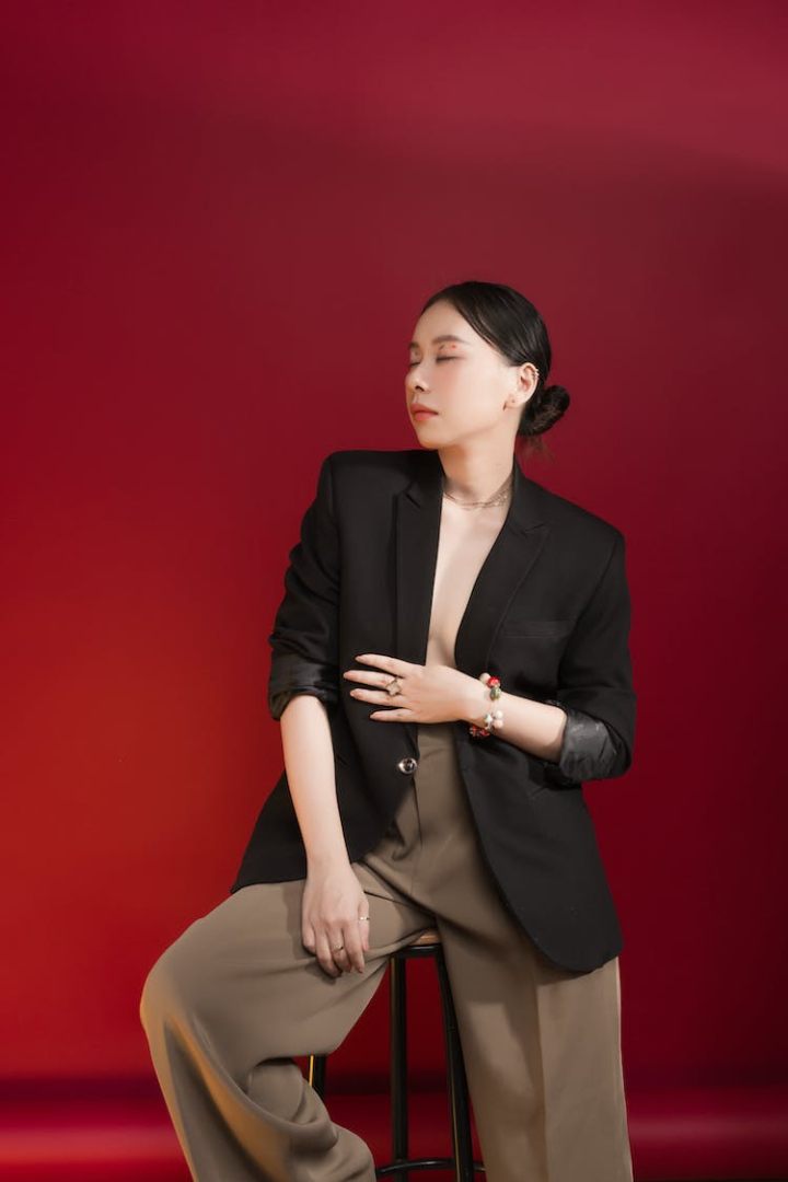 accessory,apparel,appearance,attire,bijouterie,brunette,chair,classy,cloth,copy space,elegant,ethnic,eyes closed,fashion,female,formal,garment,isolated,jacket,lady,model,outfit,pants,portrait,posh,red background,relax,respectable,rest,sit,studio,studio shot,style,suit,tranquil,trendy,trousers,vertical,vogue,wear,well dressed,woman