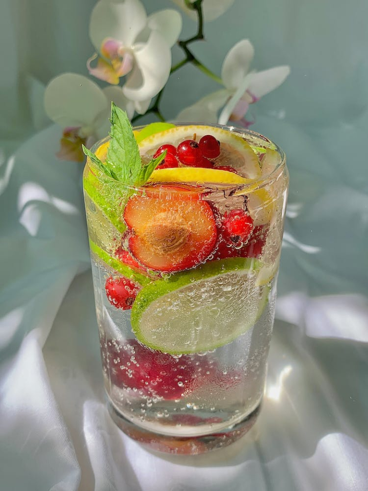 bubbles,citrus,cocktail,cold,drink,food photography,fruits,glass,icee,leaves,lemon,liquor,mint,red berries,refreshing,rum,slices,tropical,vertical shot,vodka