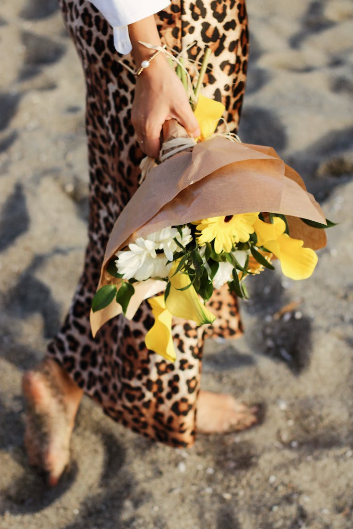 blooming,bouquet,flower,hand,holding,outside,person,sand,vertical shot