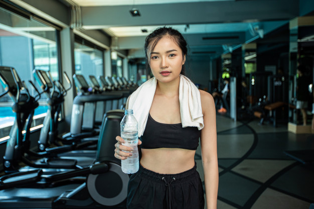 Free: Women standing and relaxing after exercise, holding a bottle