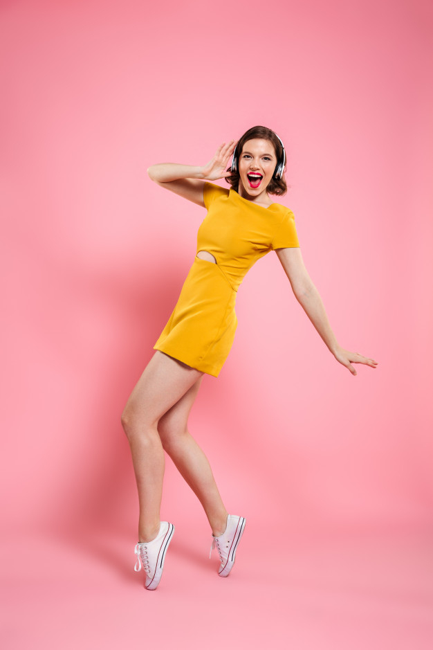 overjoyed,joying,toothy,caucasian,toes,charming,length,posing,joyful,brunette,playful,attractive,pose,cheerful,full,emotional,casual,standing,pretty,listening,adult,positive,arm,young,female,headphones,lady,lips,dress,elegant,makeup,happy,girl,fashion,woman,music
