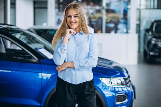 Free: Female salesperson at a car showroom by the car Free Photo - nohat.cc