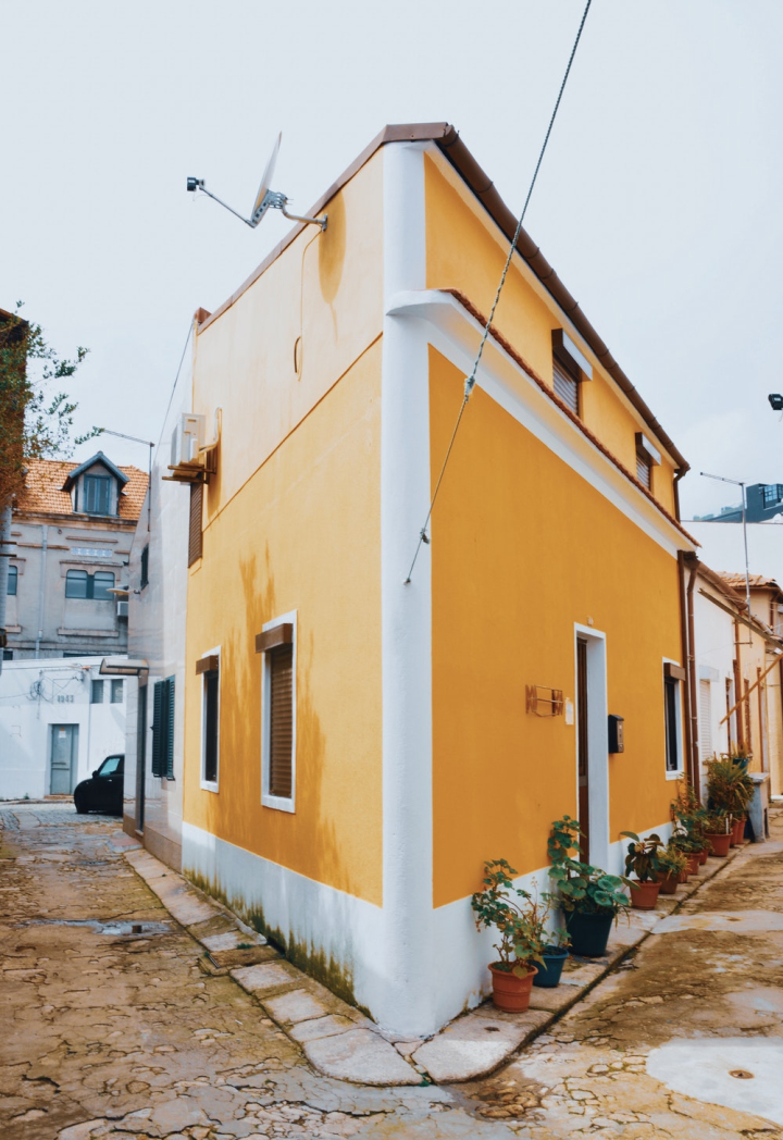 architectural design,architecture,building,city,corner,daylight,exterior,facade,family,golden yellow,home,house,outdoors,road,shape,street,town,traditional,travel,urban,window