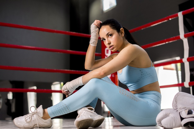 Image of Portrait Of A Young Sportive Woman Boxer In A Short Top And Boxing  Gloves Holds His Hand In A Rack And Poses On A Dark Gray  Background-CT011236-Picxy