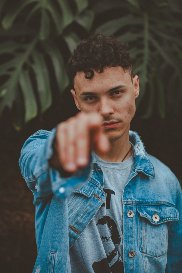 blur,casual,curly hair,denim jacket,facial expression,fashion,fine-looking,good-looking,guy,hand,handsome,male,man,model,outerwear,person,photoshoot,pointing,portrait,pose,serious,trendy,wear