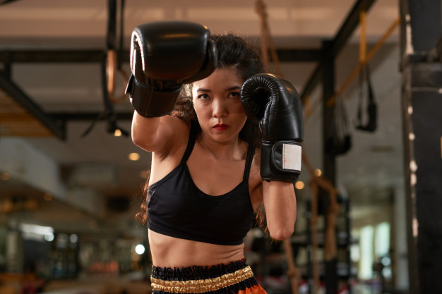 Free: Cropped asian woman training in boxing gloves at muay thai