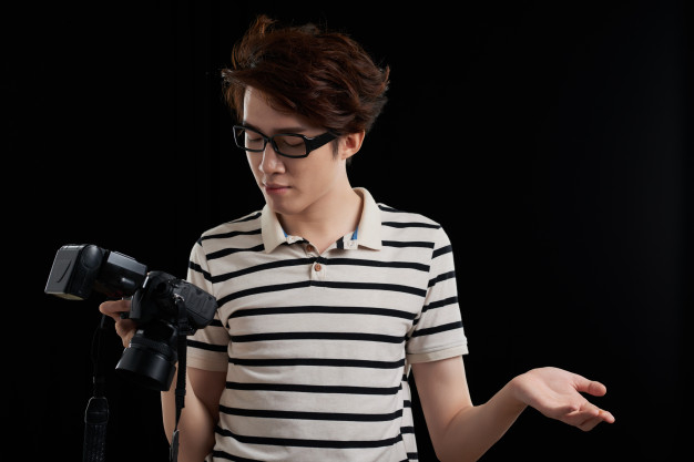 photographing,unhappy,looking,surprised,occupation,result,shooting,bad,male,journalist,confused,broken,asian,professional,young,screen,glasses,man,camera,technology