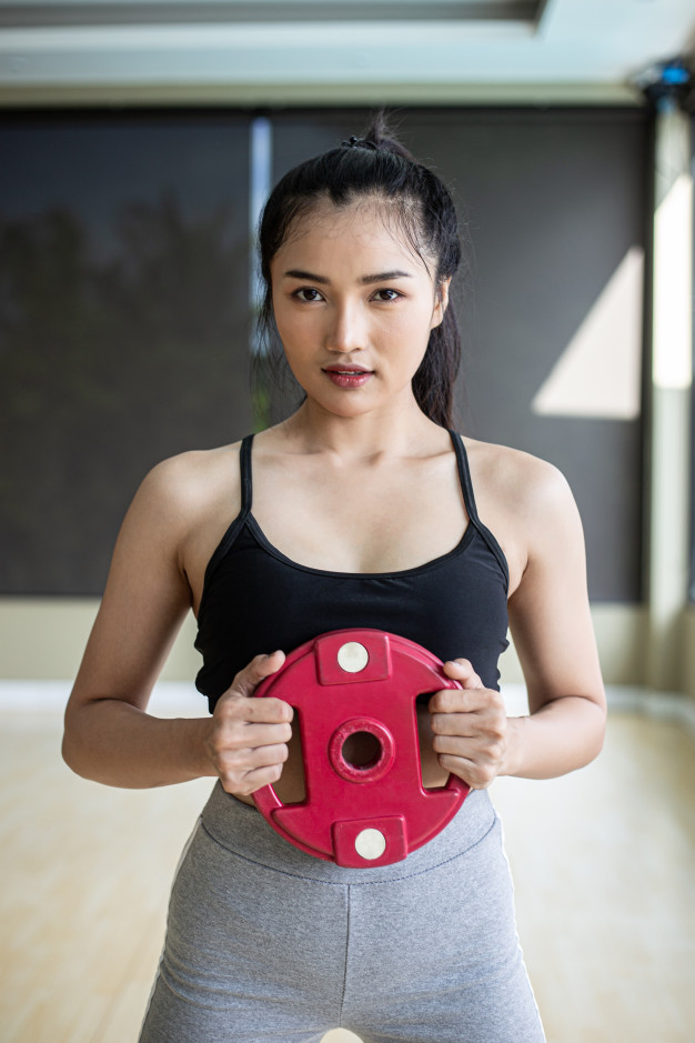 Free Women exercise with dumbbell weight plates in the chest. Free