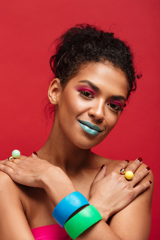 Free: Beautiful half-naked mulatto woman with fashion makeup and colorful  accessories putting crossed hands on shoulders, over red wall Free Photo 