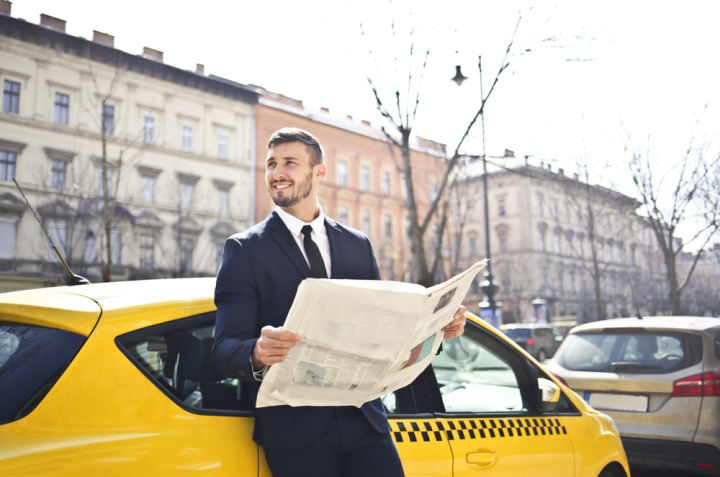 adult,businessman,man,newspaper,person,vehicle