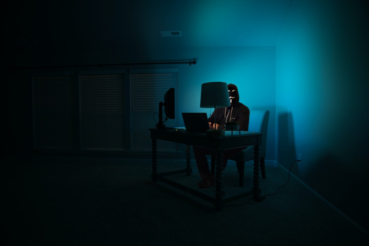 Free: Pictured - a man at a computer disguised as an anonymous hacker  wearing a Guy Fawkes mask. 