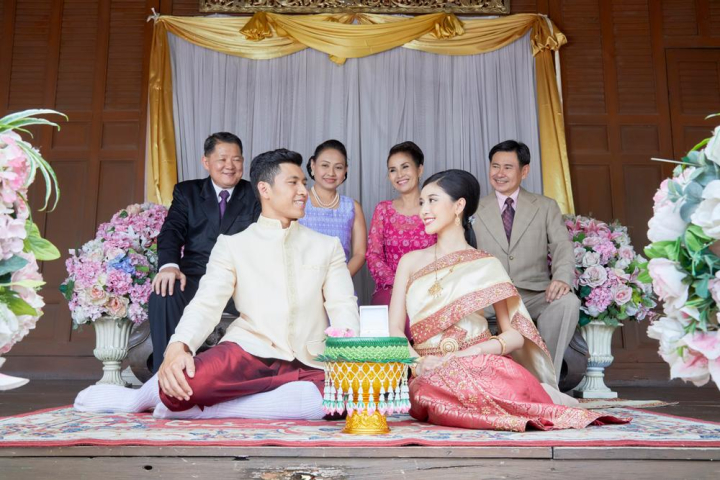 couple,looking,smiling,wedding ceremony,groom,bride,parents,wedding,thai,thailand,blessing,celebration,marriage,traditional,thai style,married,bloom,jasmine,floral,flower,arrangement,bridal,ceremony,engagement,guest,wedding reception,suit,wife,husband,happiness,female,luxury,religion,religious,carpet,curtain,white,vases,sit,gold,women,men,man,male,ring,look,wedding date,honeymoon,handsome,love,anniversary,wood,outdoor,life event,joyful,delightful,children,mother,father,mother-in-law,father-in-law,cheers,traditional costume,spouse,setting,smile,son-in-law,daughter-in-law,black,pink,grey,red,necklace,bracelet,jewelry,asia,asian,happy,romantic,family,relatives,woman,aunt,sacred,gratitude,buddhist,buddhism,decoration,dress,beautiful,elegant,elegance,together,culture,vintage,khan maak,betel bowl,xframe