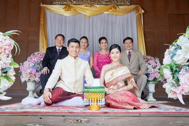 groom,bride,taking,photo,family,couple,smile,wedding ceremony,parents,wedding,thai,thailand,blessing,celebration,marriage,traditional,thai style,married,bloom,jasmine,floral,flower,arrangement,bridal,ceremony,engagement,guest,wedding reception,suit,wife,husband,happiness,setting,son-in-law,daughter-in-law,black,pink,grey,red,necklace,bracelet,jewelry,curtain,white,vases,sit,gold,women,men,man,male,ring,look,wedding date,honeymoon,handsome,love,anniversary,wood,outdoor,life event,joyful,delightful,children,mother,father,mother-in-law,father-in-law,cheers,traditional costume,spouse,asia,asian,happy,romantic,relatives,woman,aunt,sacred,gratitude,buddhist,buddhism,decoration,dress,beautiful,elegant,elegance,together,culture,vintage,female,luxury,religion,religious,carpet,khan maak,betel bowl,xframe