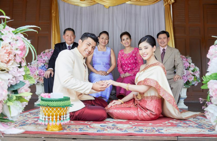 groom,bride,holding,hand,sitting,looking,smiling,together,wife,congratulation,thailand,vintage,people,bridal,asia,asian,thai,religion,religious,celebration,wearing,jasmine,flower,pot,sacred,happiness,elegant,engagement,group,six,dress,female,man,woman,buddhist,buddhism,wedding,mariage,married,custom,ring,finger,family,relatives,husband,front,parents,beautiful,male,couple,love,decoration,thai style,traditional,culture,blessing,ceremony,floral,khan maak,betel bowl,xframe